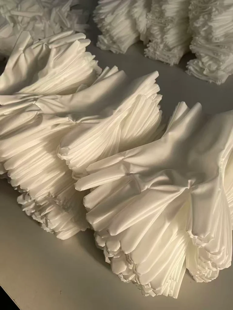 Cleanroom gloves stacked neatly on a table in a controlled environment. クリーンルーム手袋が整然と積み重ねられている様子